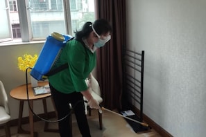 A person cleaning a room with a vacuum cleaner. - Silver Lake Hotel (Zhuhai Jinwan Airport) (Zhuhai)