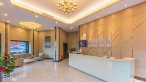 Un moderno vestíbulo de hotel con una recepción, zona de estar y una pantalla grande.