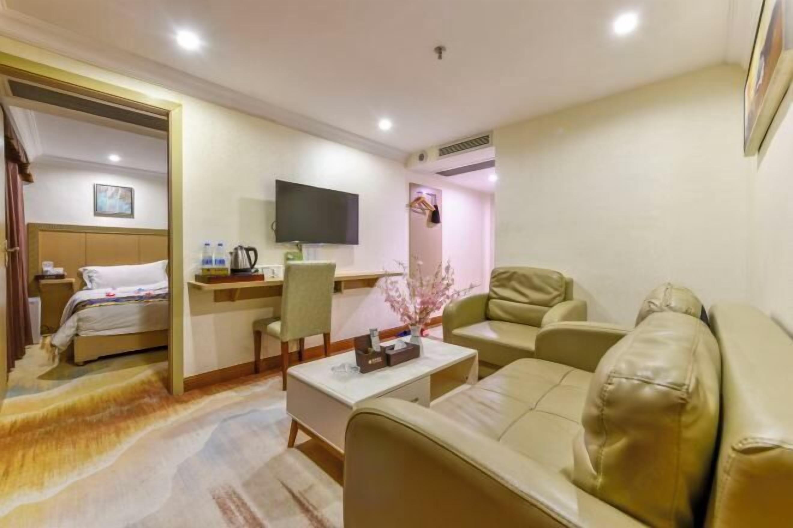 A hotel room with a bed, a desk with a chair, a sofa, and a television.