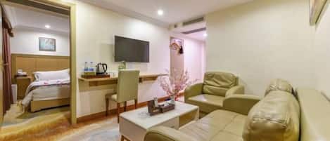 A hotel room with a bed, a desk with a chair, a sofa, and a television.