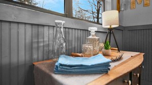 Et træbord dækket med et blåt stof, en lampe og dekorative genstande, heriblandt en vase og en plante.