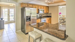 Una cocina moderna con encimeras de granito, electrodomésticos de acero inoxidable y armarios de madera.