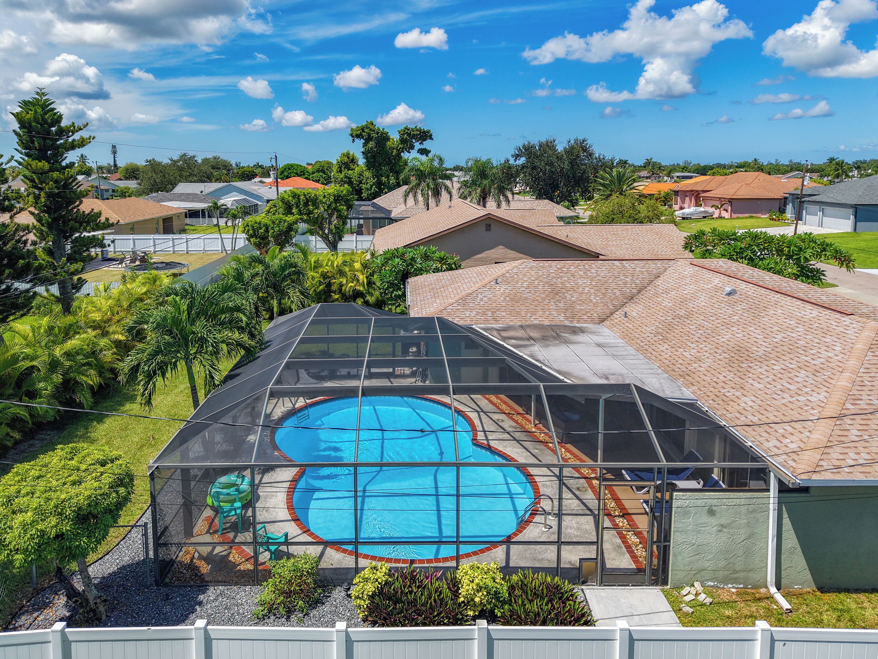 Zona residencial con piscina, rodeada de vegetación y viviendas.