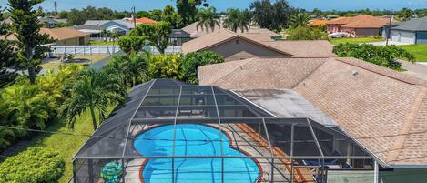Zona residencial con piscina, rodeada de vegetación y viviendas.