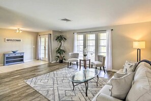 A living room with a sofa, a glass coffee table, a rug, a plant, and a 'WELCOME' sign. - Heated Private Pool • Prime Cape Coral Location • Relax & Unwind (Cape Coral)