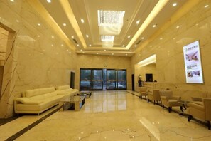 A hotel lobby with a marble floor, a reception desk, a sofa, and a seating area. - Jinbiwan Hostel (Kaiping)