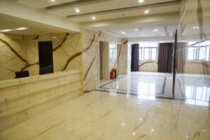 A hotel lobby with marble flooring, a reception desk, and a glass partition. - Jinbiwan Hostel (Kaiping)