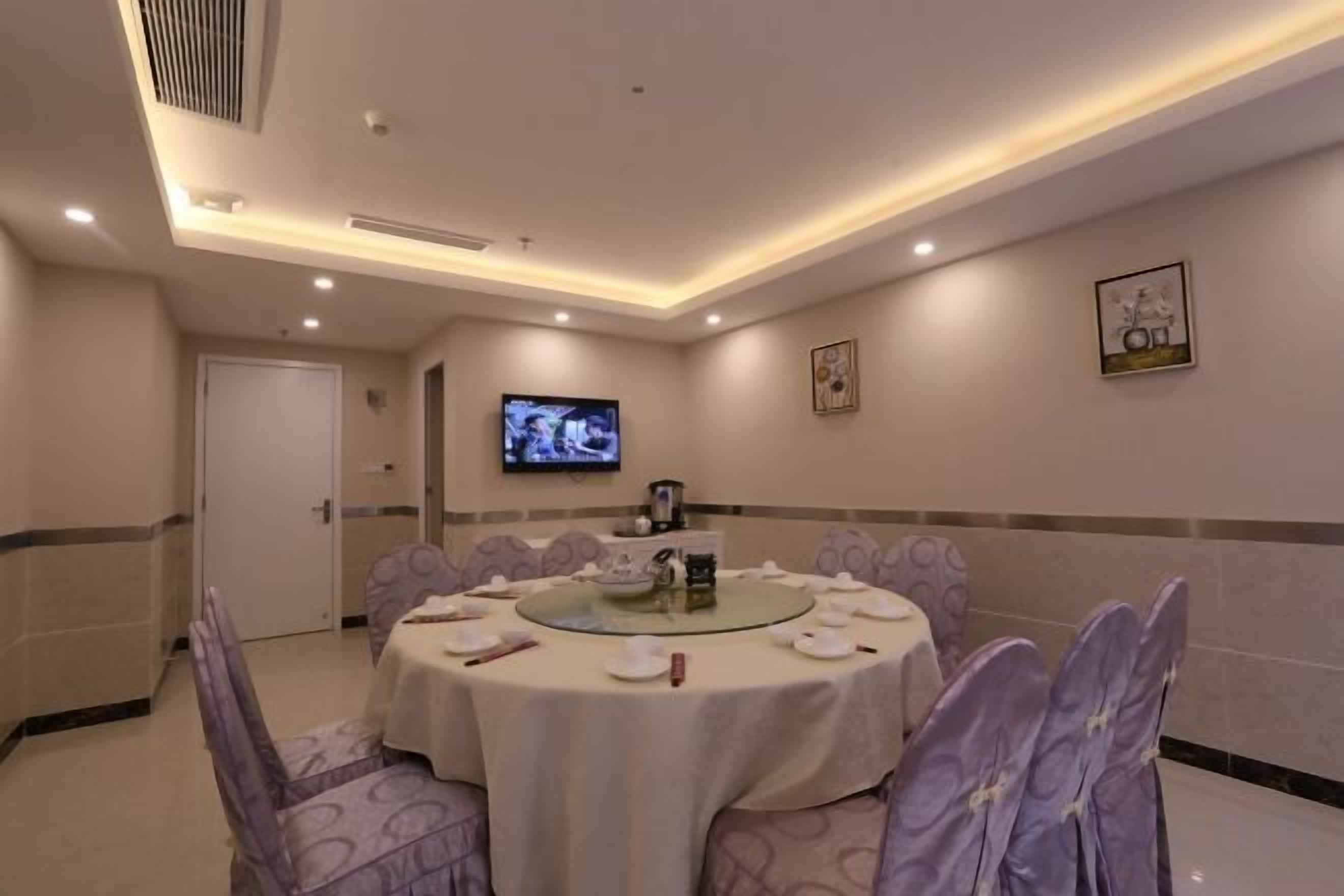 A conference room with a round table, chairs, a television, and framed artwork on the walls.