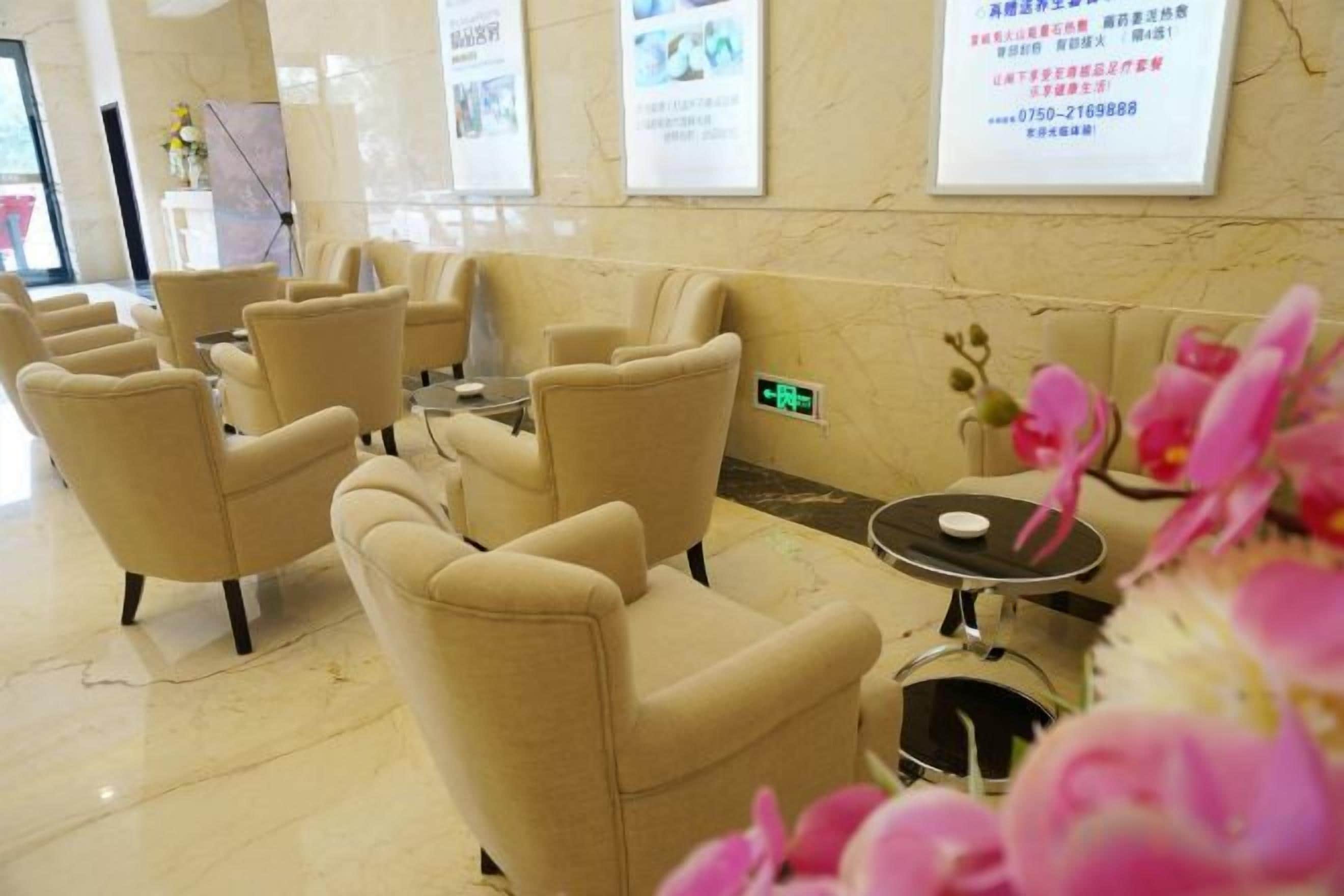 Un'accogliente hall d'albergo con diverse zone relax, una reception e manifesti informativi alle pareti.