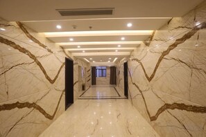 A hallway with marble walls and a polished floor, leading to a door at the end. - Jinbiwan Hostel (Kaiping)