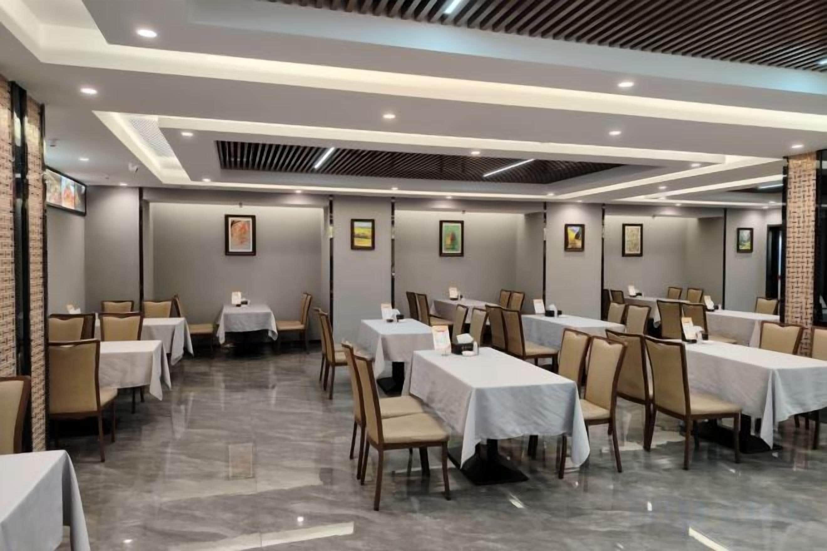 A hotel dining area with multiple tables and chairs, arranged in a spacious layout.