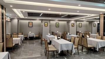 A hotel dining area with multiple tables and chairs, arranged in a spacious layout.