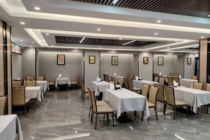 A hotel dining area with multiple tables and chairs, arranged in a spacious layout. - Jinbiwan Hostel (Kaiping)