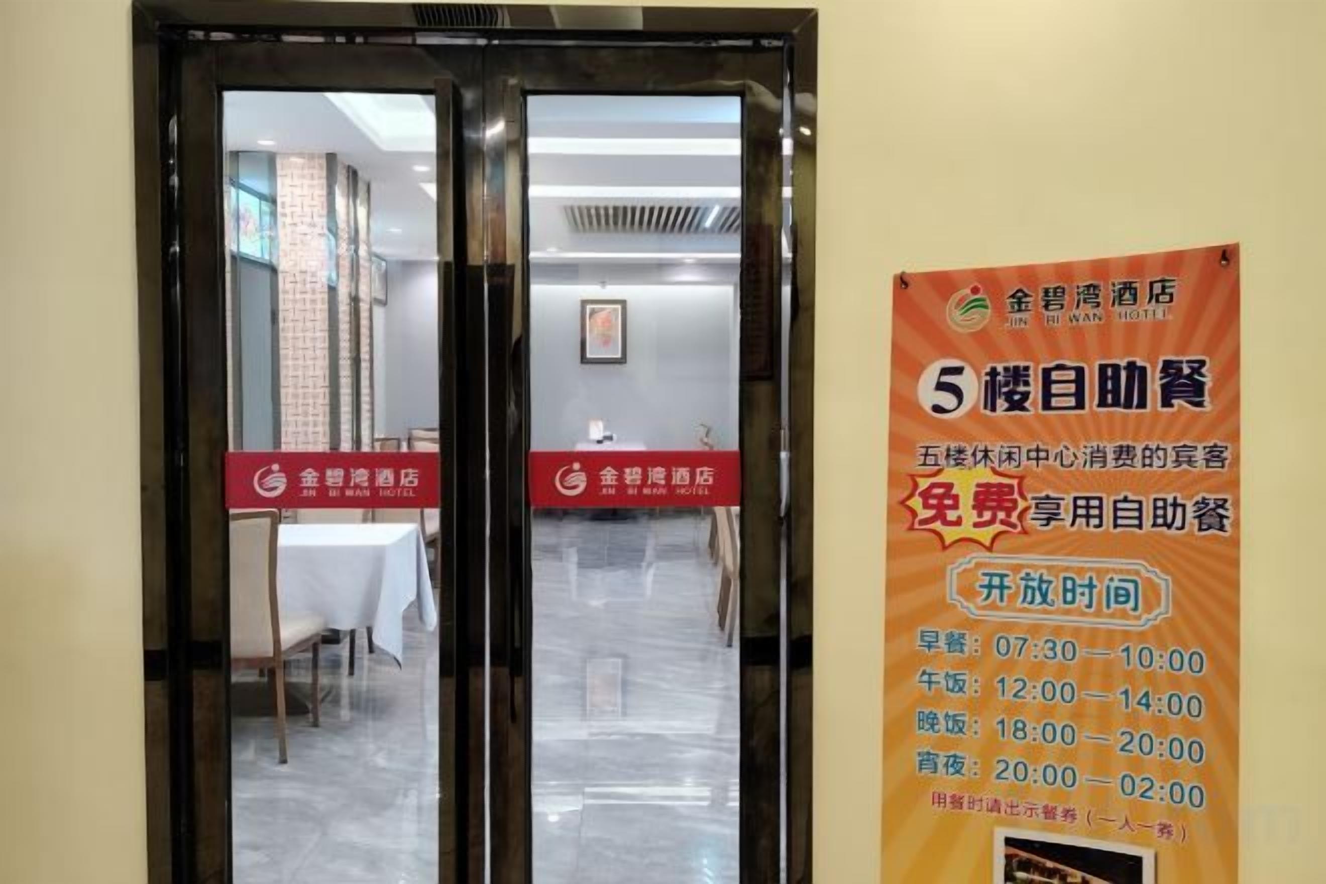 A hotel entrance with a glass door and a poster advertising free self-service breakfast.