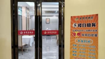 A hotel entrance with a glass door and a poster advertising free self-service breakfast.