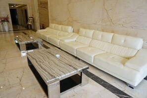 Un hall con un sofá de cuero blanco y dos mesas de centro de mármol.