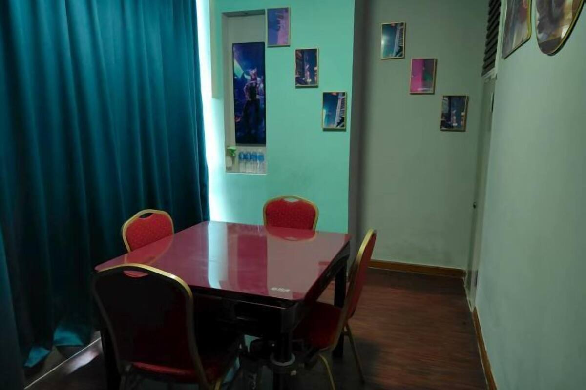 Een vergaderruimte met een glazen tafel en rode stoelen, een blauw gordijn en posters aan de muur.
