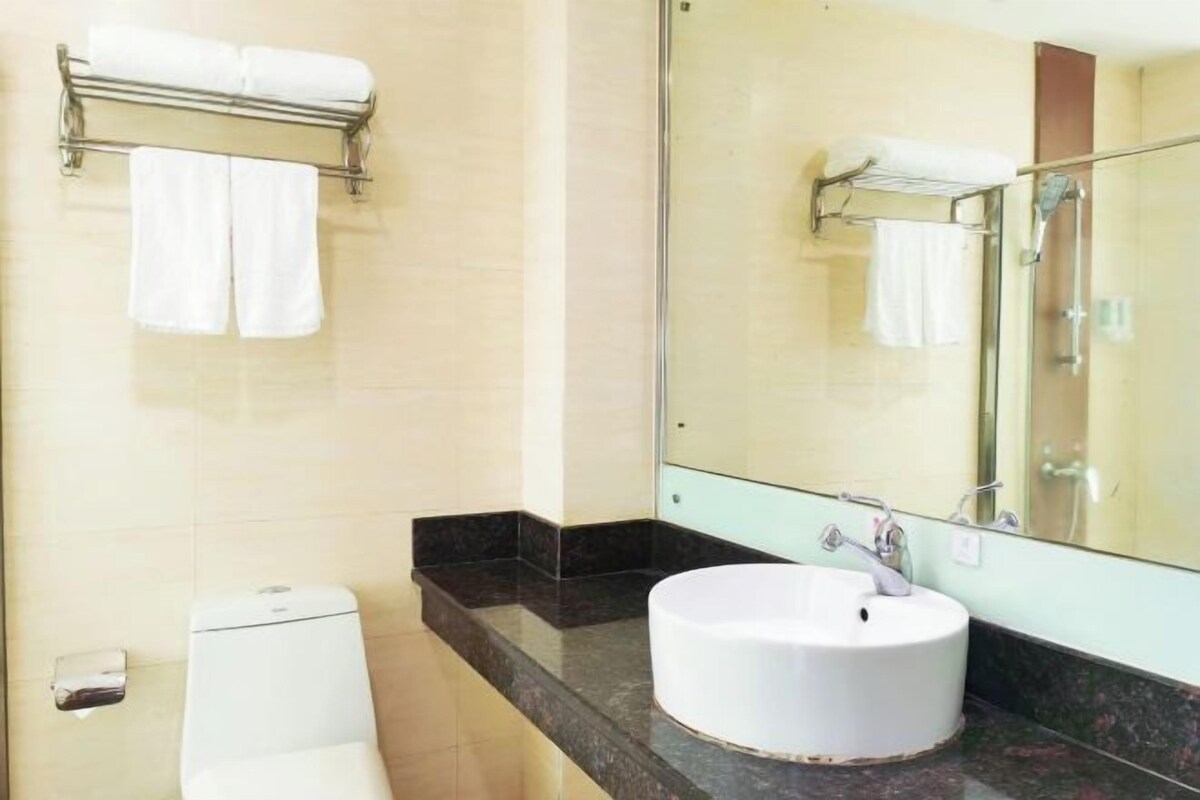 Un bagno con il water, un lavandino, uno specchio e un portaserviti.