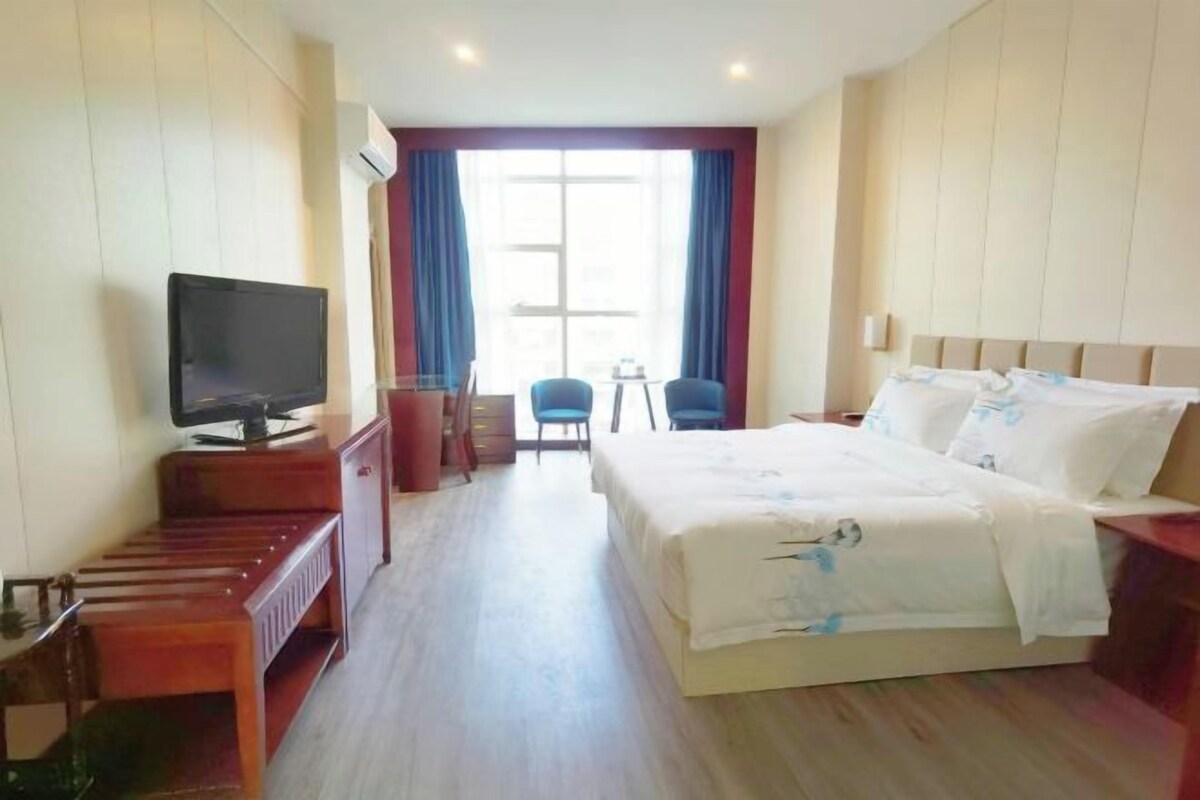 A hotel room with a bed, a TV, a desk, and a chair.