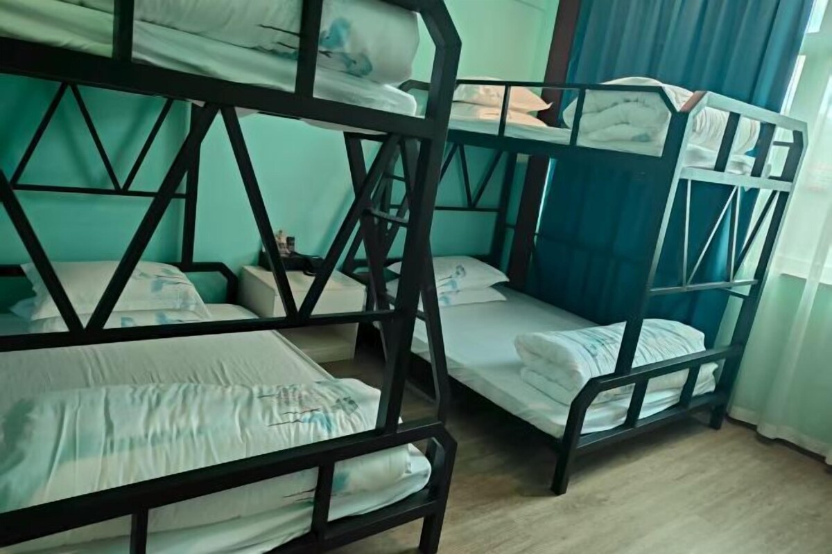 A bunk bed room with a geometric wall design, a nightstand, and a window with curtains.