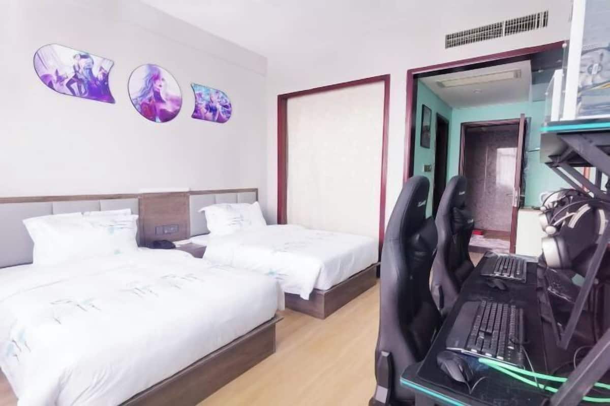 Een hotelkamer met twee bedden, een bureau met een computer en wanddecoratie.