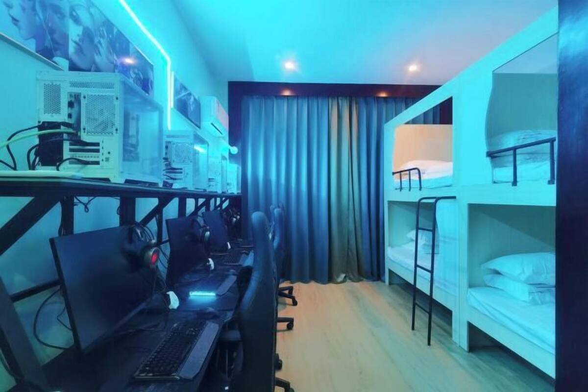 Een kamer met stapelbedden, een bureau met computers en een gordijn.