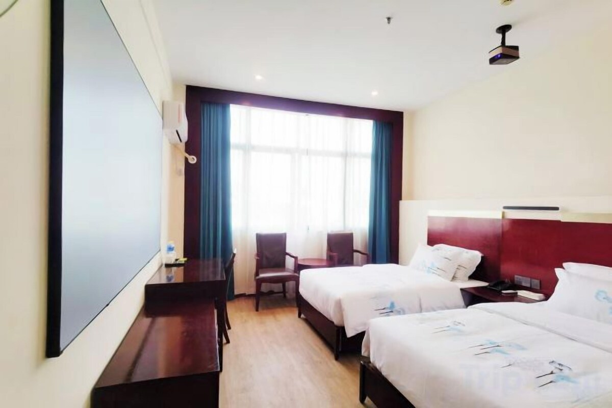 A hotel room with two beds, a desk, and a chair.
