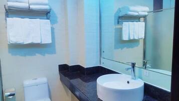 Un baño con un lavabo blanco, un inodoro y un perchero con toallas dobladas.