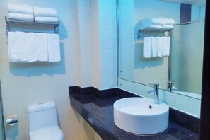 A bathroom with a white sink, a toilet, and a towel rack with folded towels.