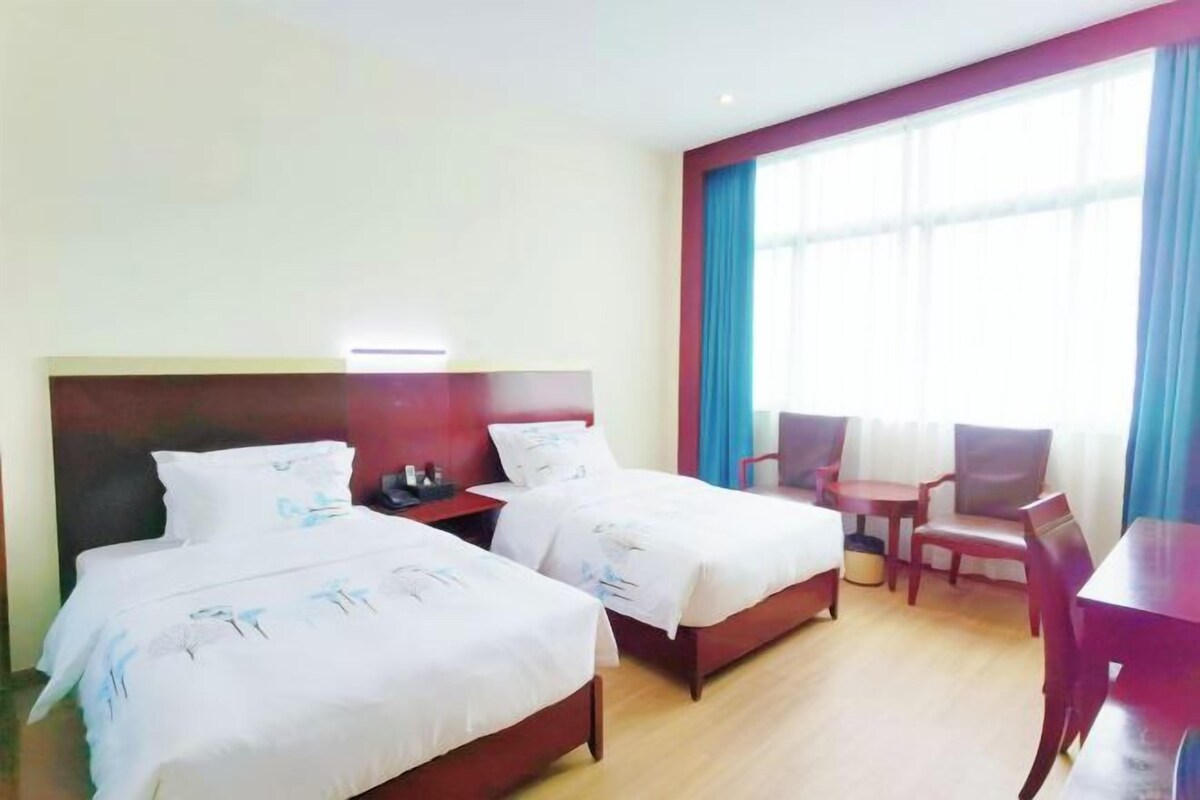 A hotel room with two beds, a desk, and a chair.