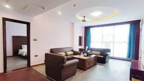 A hotel room with a bed, two sofas, a coffee table, and a large window with curtains.