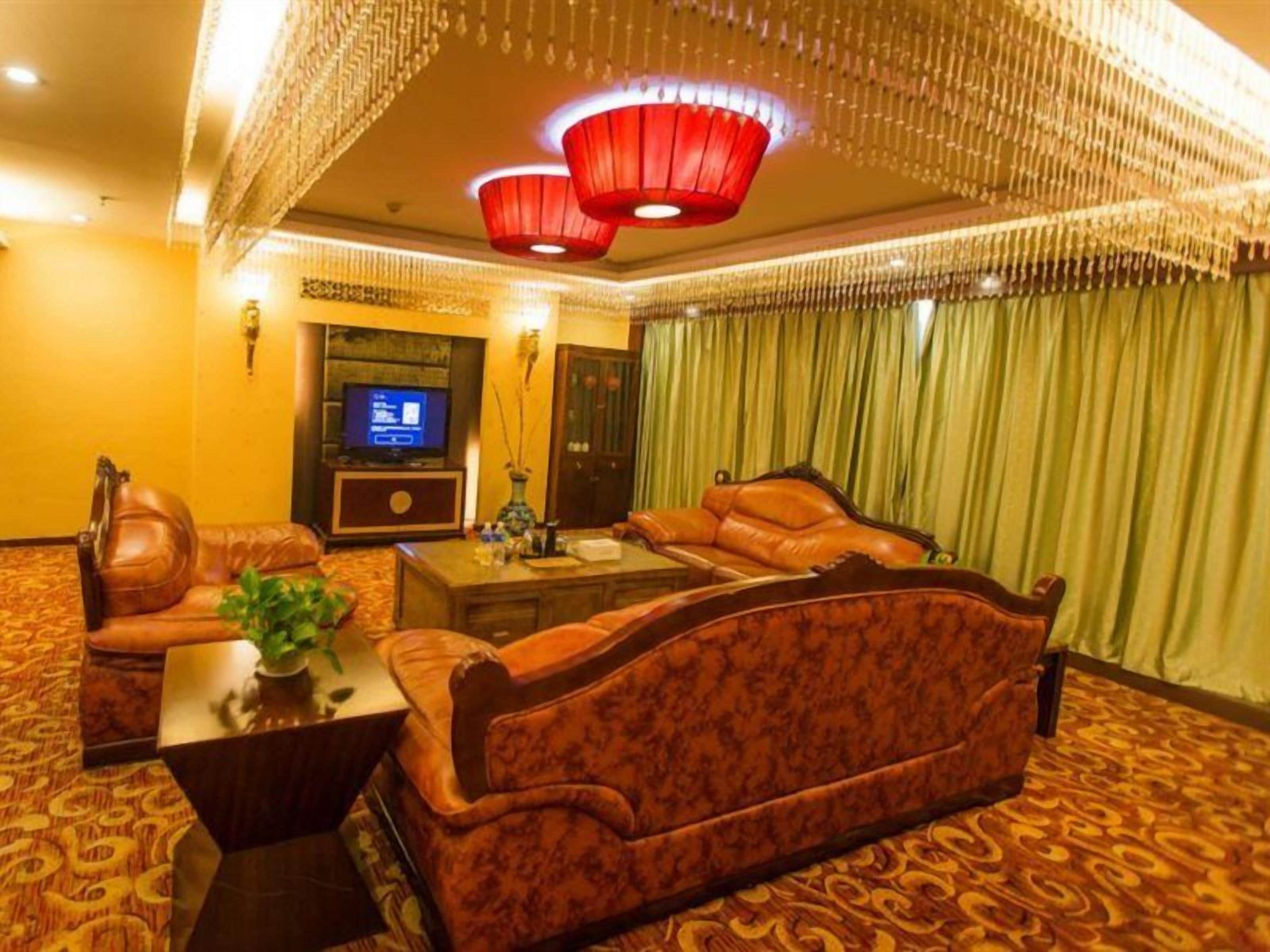 Une chambre d’hôtel avec un grand canapé, une télévision et un plafond décoratif.