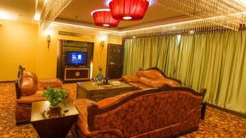 Habitación de hotel con un sofá grande, un televisor y un techo decorativo.