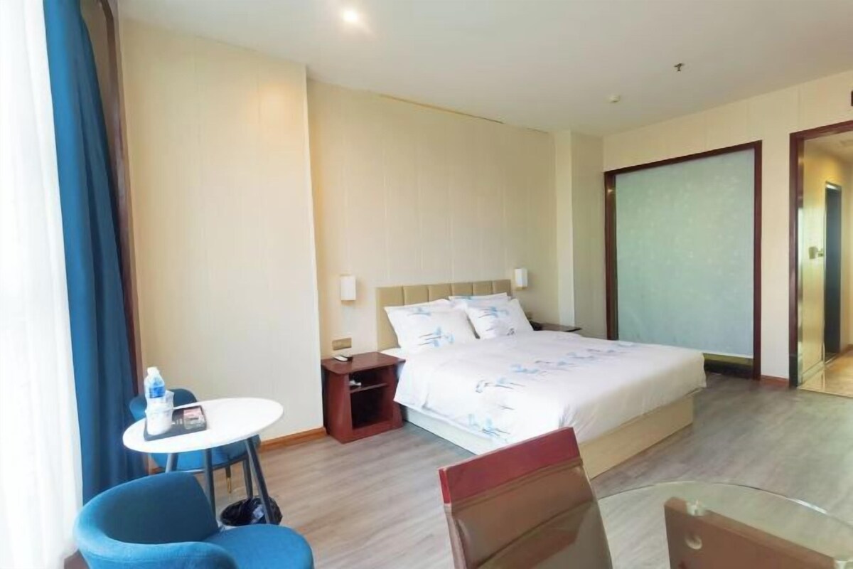 Una camera d'albergo con un letto, un tavolino, una sedia e un armadio.