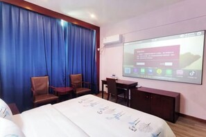 A hotel room with a bed, two chairs, a desk, and a large screen displaying a presentation. - Deyuan Hotel (Shaoguan Nanhua Temple) (Shaoguan)