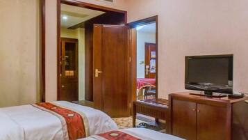 Una habitación de hotel con dos camas, un armario de madera, un televisor y un espejo.