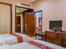 Una habitación de hotel con dos camas, un armario de madera, un televisor y un espejo.