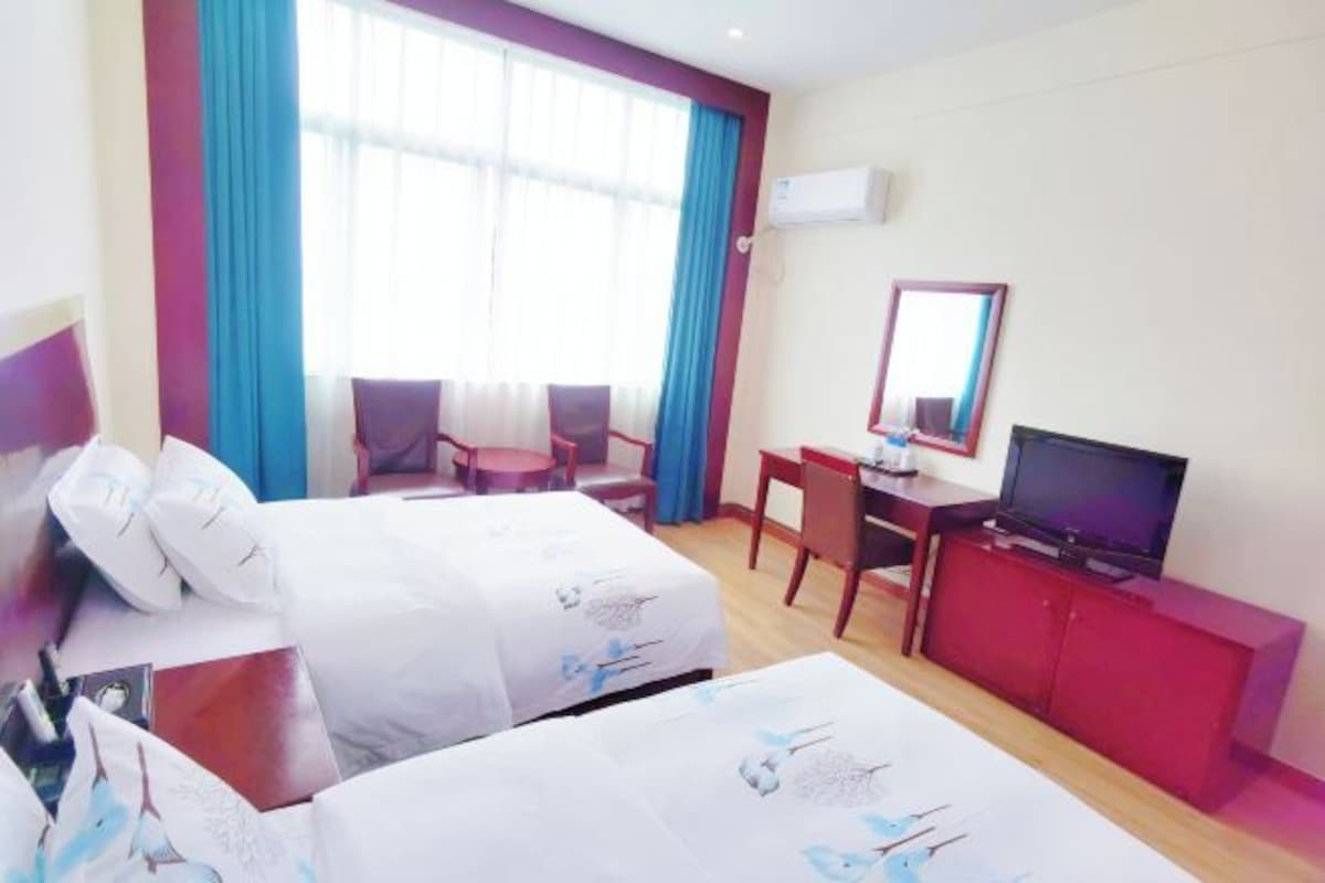 Una habitación de hotel con dos camas, un escritorio, un televisor y un armario rojo.