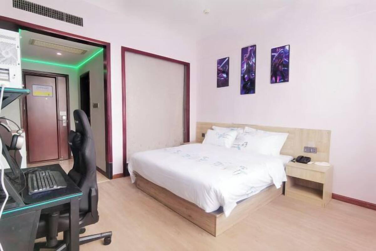 Een hotelkamer met een bed, een bureau met een computer, een stoel en een nachtkastje.