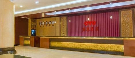 A hotel reception area with a marble floor, a reception desk, and a red wall with the hotel name.
