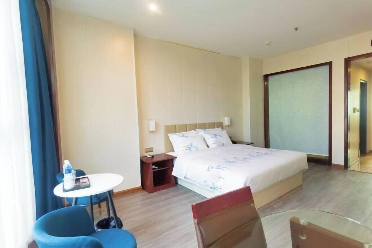 Een hotelkamer met een bed, een kleintje tafel, een stoel en een kast.