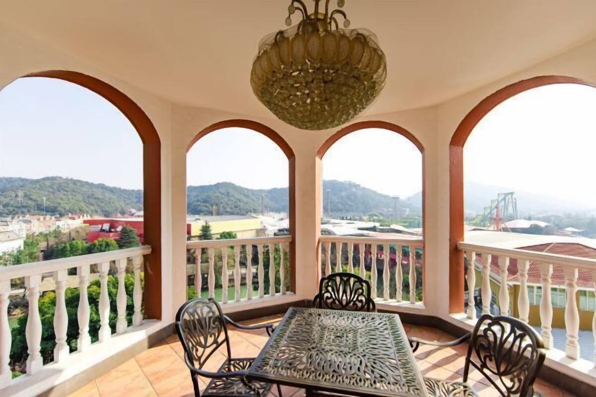 A balcony with a table and chairs, offering a view of a mountainous landscape.