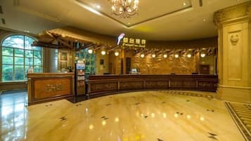 A reception desk with a chandelier, a reception area, and a marble floor with directional arrows.
