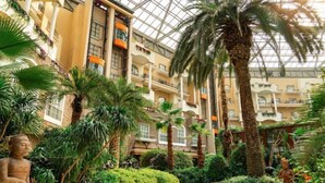 A multi-level atrium with palm trees, a statue, and a glass ceiling. - the First World Hotel (Songcheng Hangzhou Paradise Tourist Area) (Hangzhou)