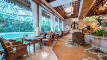 A hotel lobby with a long dining area, large windows, and a reception desk.