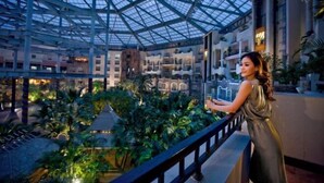 An indoor atrium with a glass ceiling, a balcony with a railing, and lush greenery. - the First World Hotel (Songcheng Hangzhou Paradise Tourist Area) (Hangzhou)