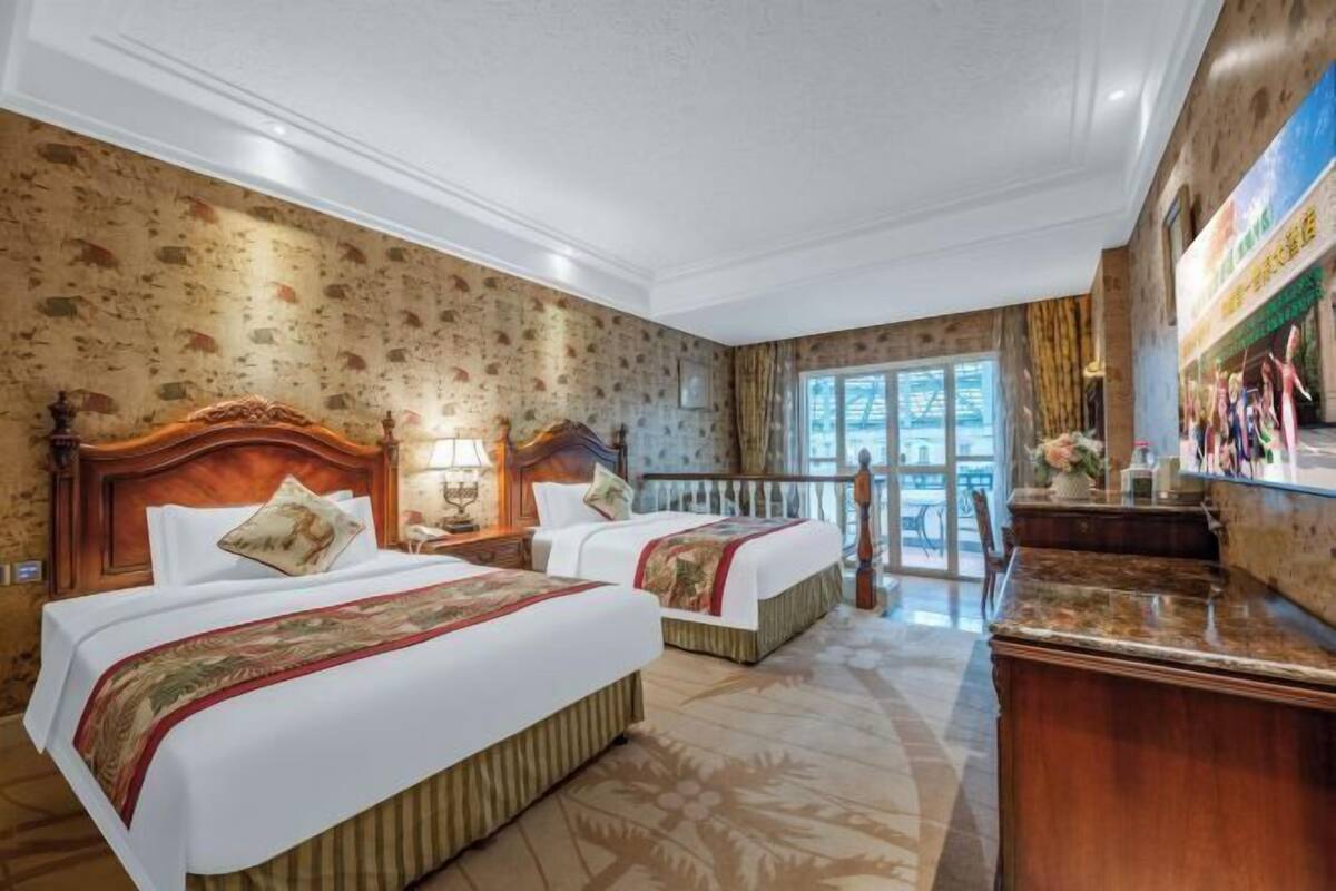 A hotel room with two beds, a wooden headboard, a large window, and a balcony.