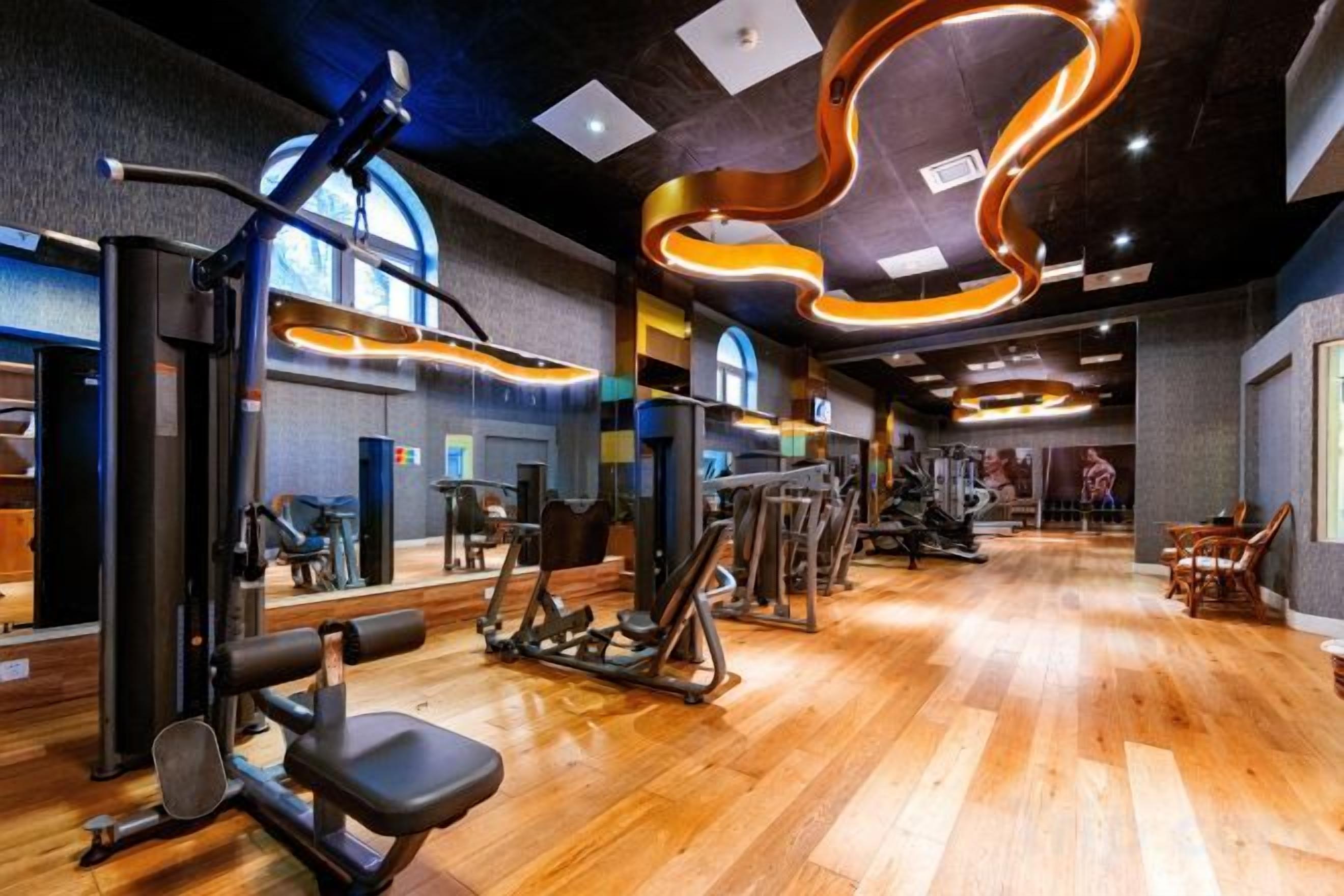 A gym with exercise equipment, wooden flooring, and a modern ceiling design.