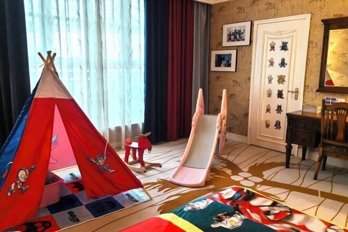 A room with a bed, a red and blue teepee, a rocking chair, a door with animal stickers, and a patterned rug.