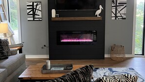 Ein modernes Wohnzimmer mit Kamin, Flachbildfernseher und abstrakten Wandbildern.